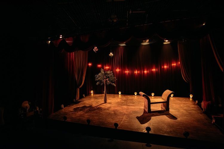 Empty set of Red Velvet with red lighting and a bench in the middle of the stage